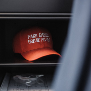 Eine rote Kappe mit der Aufschrift "Make America great agian" liegt in einem Regal.