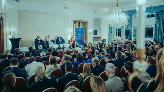 Publikum lauscht einer Podiumsdiskussion in einem historischen Saal.